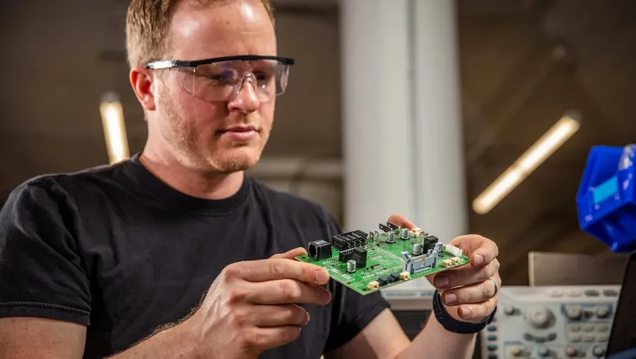 An electronics engineer working on a computer with PCB design software open.