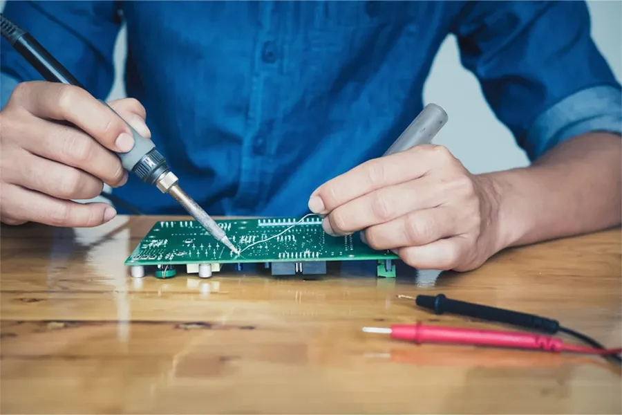 Hands soldering components onto a PCB.