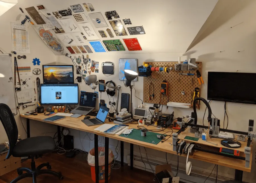 An engineer working at a workstation with PCB design tools and equipment.