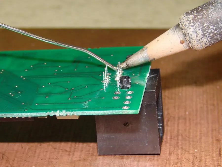 A person soldering electronic components onto a circuit board.